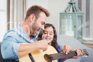 Father playing guitar with daughter