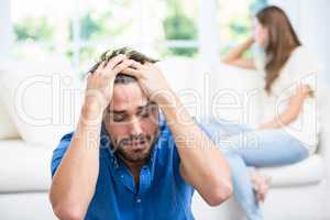 Tensed man sitting on floor after argument with wife