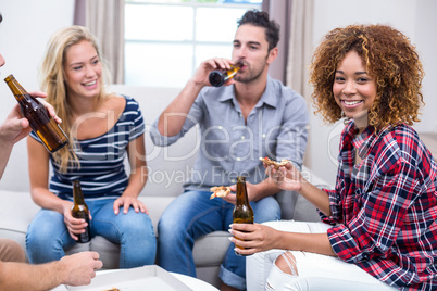 Young woman enjoying beer and pizza with friends