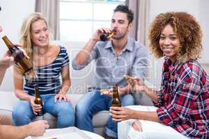 Young woman enjoying beer and pizza with friends