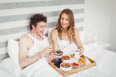 Young couple having breakfast on bed