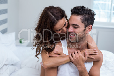 Smiling couple hugging on bed