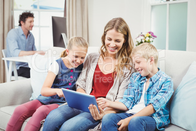 Children looking in digital tablet while sitting with mother