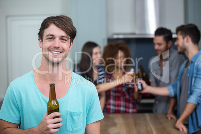 Happy man holding beer bottle while friends in background