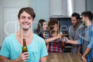 Happy man holding beer bottle while friends in background