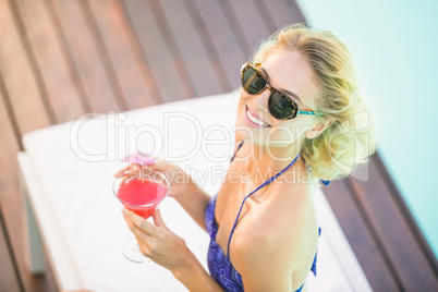 Portrait of beautiful woman with cocktail sitting on sun lounger