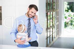 Businessman talking on cellphone while holding daughter