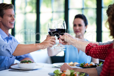 Happy friends toasting wine glass while having lunch