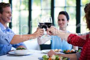 Happy friends toasting wine glass while having lunch