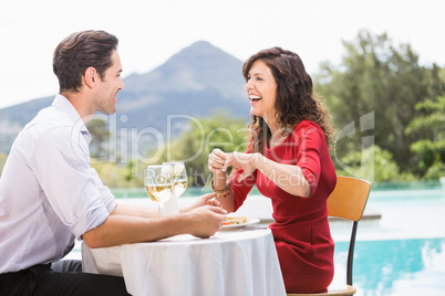 Cheerful couple sitting by swimming pool