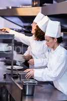 Two chefs working at order station in a kitchen