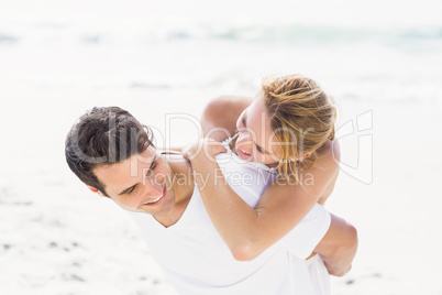 Man giving a piggy back to woman on the beach