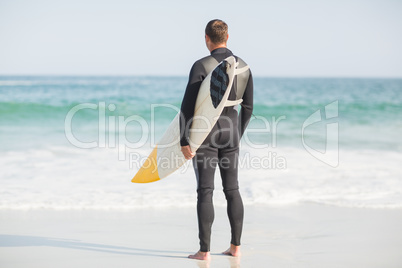 Surfer standing on the beach with a surfboard