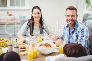 Smiling parents with children sitting at dining table
