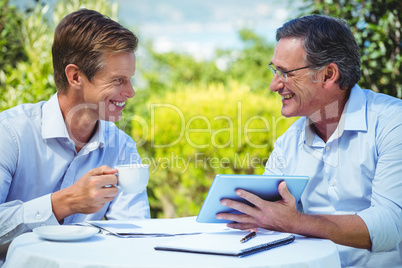 Two businessmen meeting in a restaurant using tablet