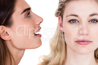 Close-up of woman telling secret to friend