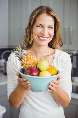 Portrait of happy woman holding fruit bowl