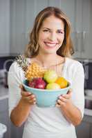 Portrait of happy woman holding fruit bowl