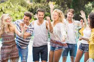 Group of happy friends dancing near pool