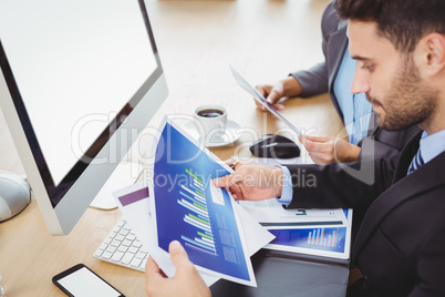 Businessman analyzing graph at computer desk