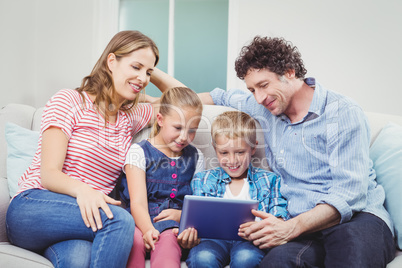 Family smiling and looking in digital tablet