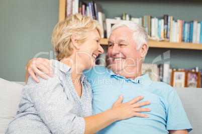 Senior couple smiling while hugging on sofa