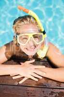 Happy woman with snorkel gear leaning on pool side