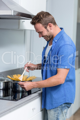 Young man cooking spaghetti