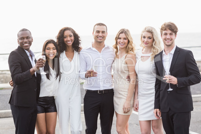 Well dressed people posing next to a limousine