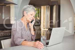 Serious senior woman talking on mobile phone