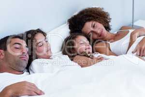 Family sleeping together on bed