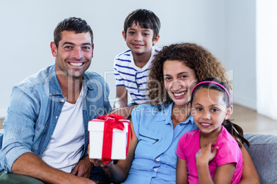 Portrait of family sitting on sofa with a gift