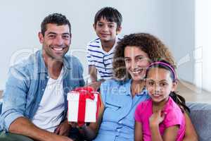 Portrait of family sitting on sofa with a gift