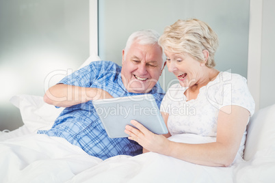 Excited senior couple using digital tablet at home