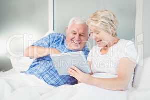 Excited senior couple using digital tablet at home