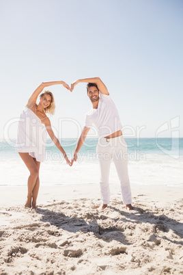 Smiling young couple doing heart shape