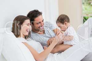 Cheerful couple playing with baby girl