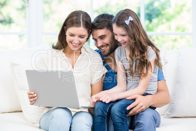 Family sitting on sofa and looking at laptop