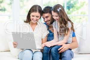 Family sitting on sofa and looking at laptop