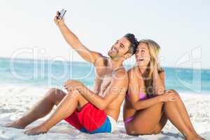 Happy couple sitting back to back on beach