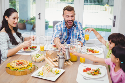 Smiling family sitting at dining table with food