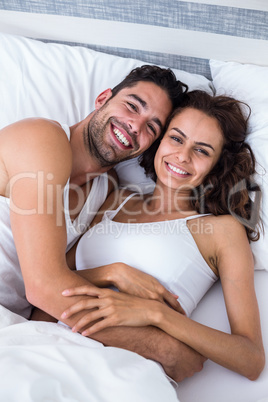 Portrait of cheerful couple relaxing on bed