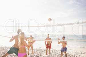 Happy friends playing beach volleyball