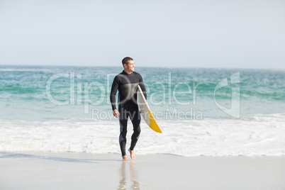 Surfer walking on the beach with a surfboard