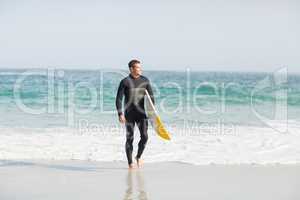 Surfer walking on the beach with a surfboard