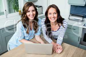 Portrait of smiling female friends working on laptop