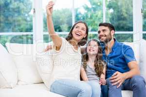 Family clicking selfies while sitting on sofa