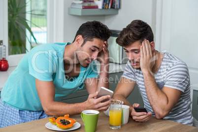 Frustrated male friends using phone