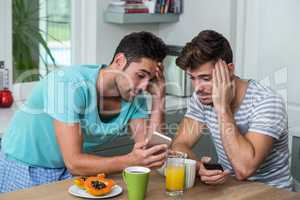 Frustrated male friends using phone