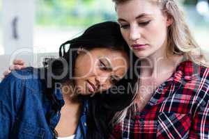 Young woman consoling depressed female friend at home